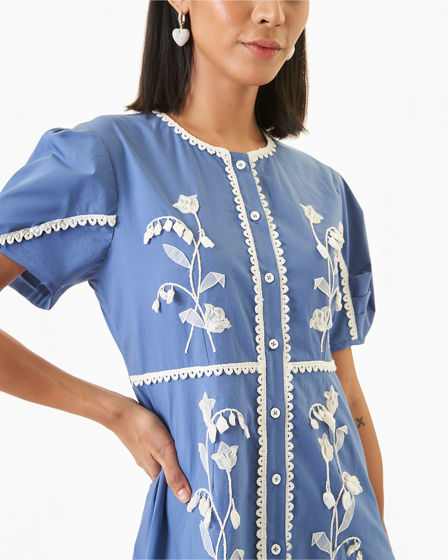 Close-up of Daffodil Dress - Blue Cotton Dress showing detailed white lace embroidery and pearl-style front buttons on soft cotton.